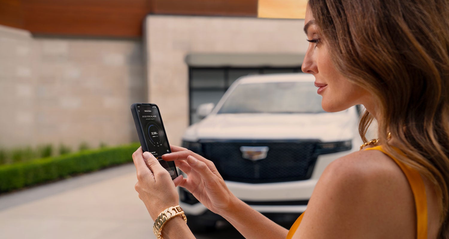lady checking her mobile with a Cadillac vehicle background | Ritchey Cadillac in DAYTONA BEACH FL