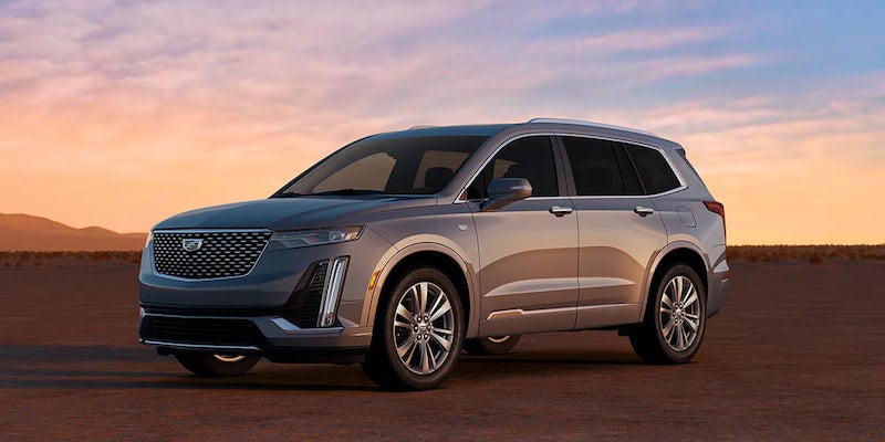 Front angle of the 2025 Cadillac XT6 driving on a scenic desert highway during golden hour